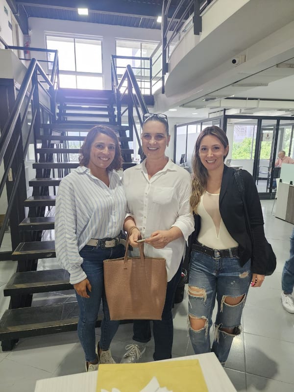 Tres mujeres posando junto a una escalera metálica en una oficina