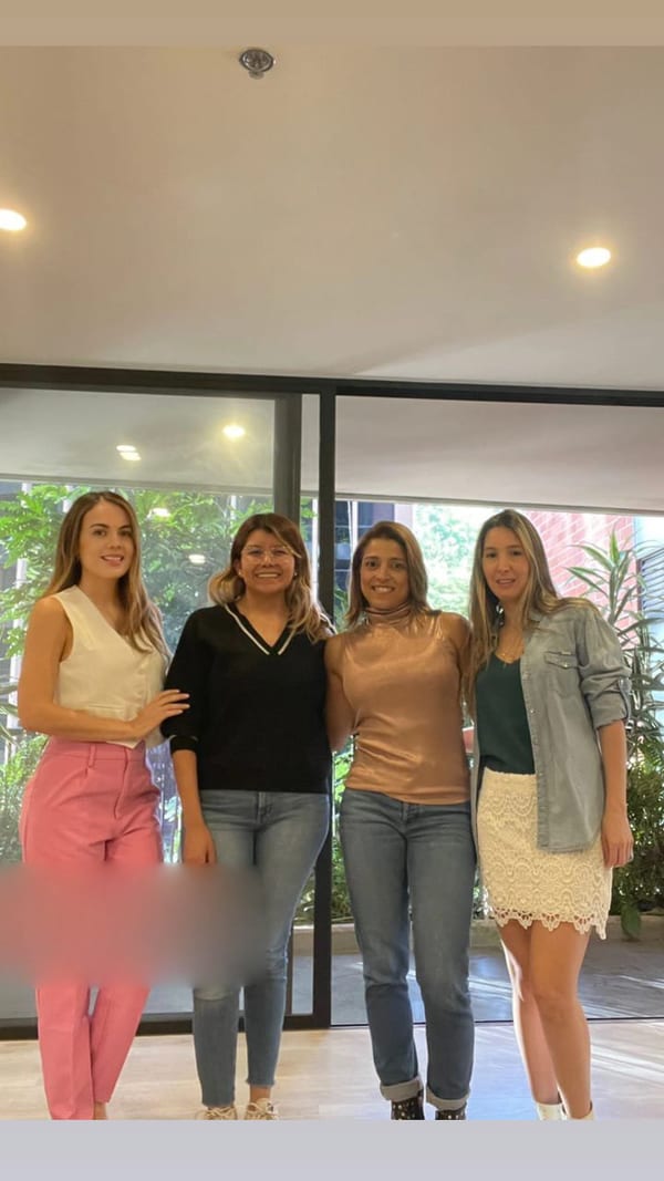 Cuatro mujeres posando en un espacio interior con grandes ventanales